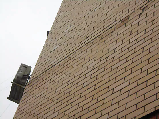 Трещины и сколы в кирпиче в узлах крепления облицовки к бетонным панелям здания