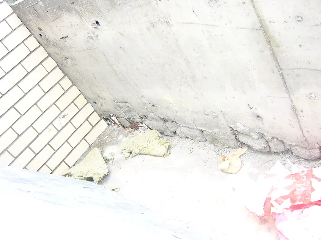 Непровибрированный в основании бетон, не подготовленная поверхность под бетонной стеной (неубранный строительный мусор)