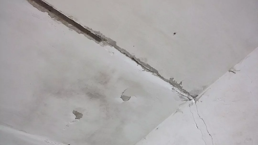 Трещина между плитами перекрытия административного здания, переходящая на стену