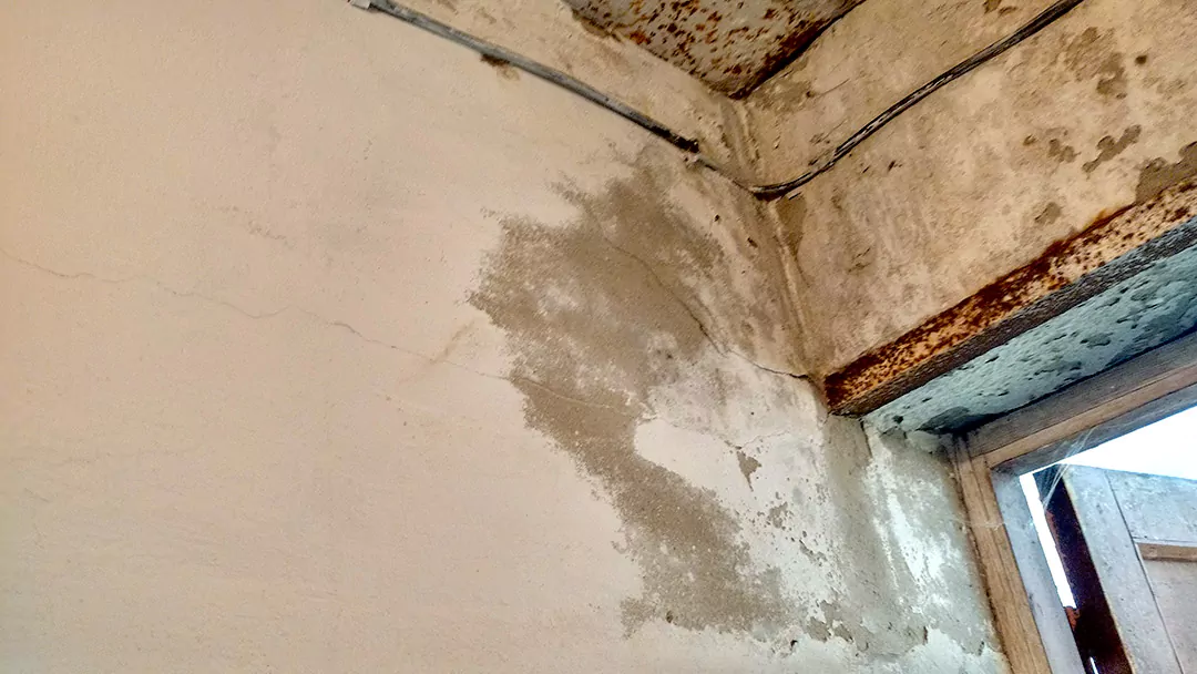 Разрушение отделочного слоя стен подсобки и трещина по стене, идущая от угла дверного проема